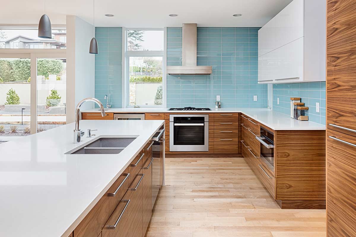 Modern kitchen with natural wood cabinet faces and a teal glass tile backsplash
