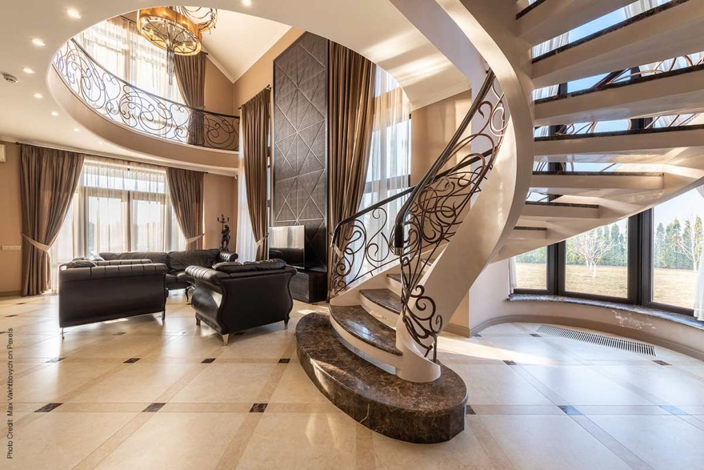 Elegant curved staircase with scroll-style handrails and marble treads in an upscale home