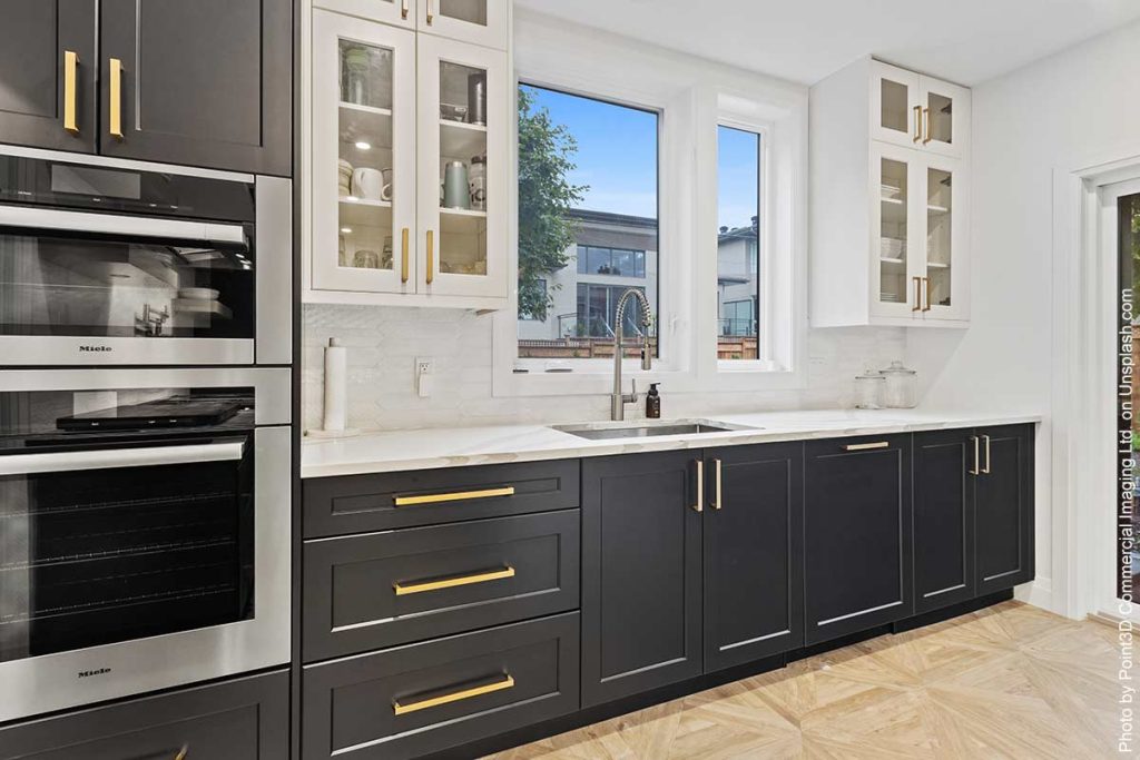 Kitchen following design trend of dark cabinet fronts with natural stone countertops