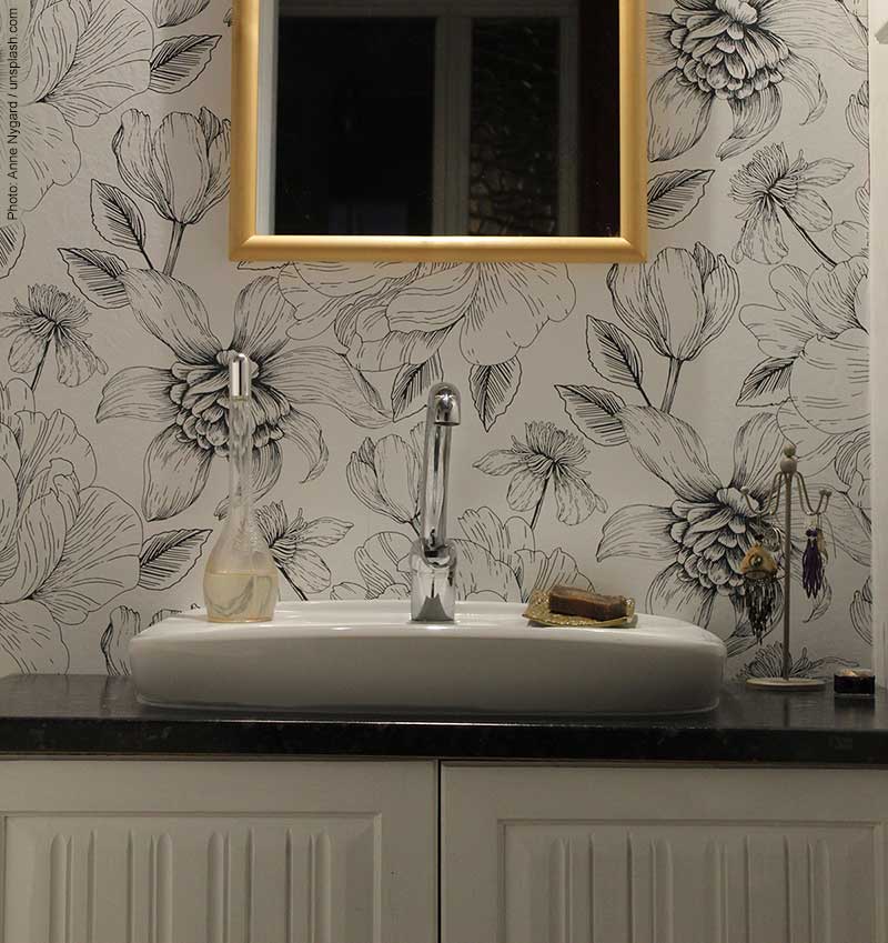 Floral wallpaper in a powder room with unique flat sink is on trend